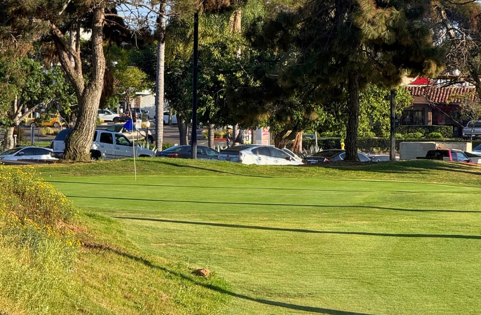 Golf green with blue flag near clubhouse parking area at National City Golf Course